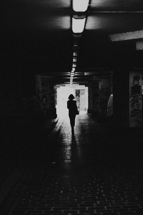 Free Moody black and white silhouette of a woman in an urban tunnel. Reflects introspection. Stock Photo