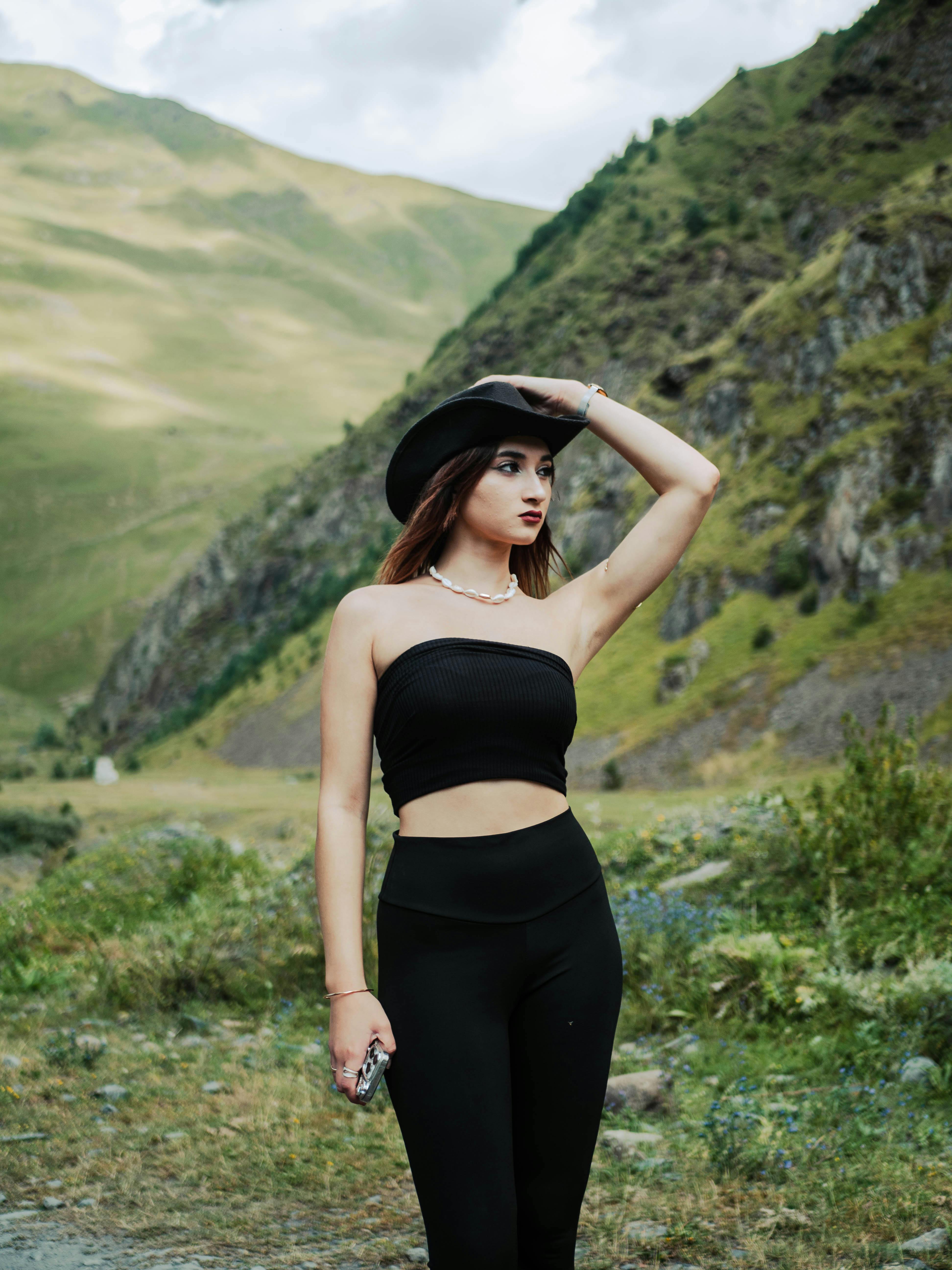 model in black tube top and leggings holding her hat