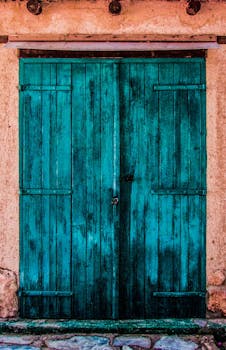 A vibrant, rustic blue wooden door on a textured, weathered wall.