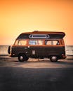 日落时分，一辆经典的大众露营车停在海边