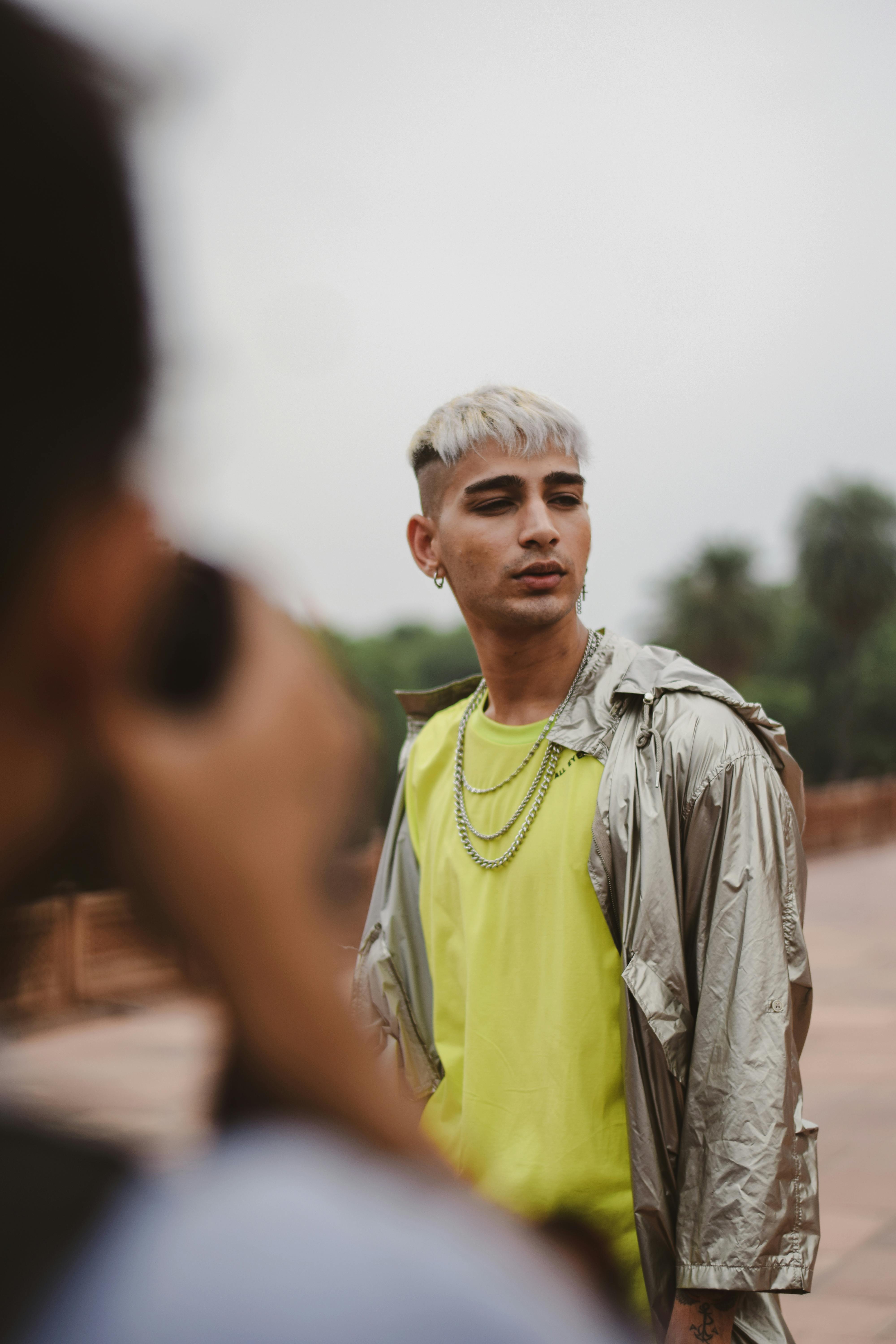 穿着明亮衣服的时尚男人在户外摆出姿势，专注于现代时尚