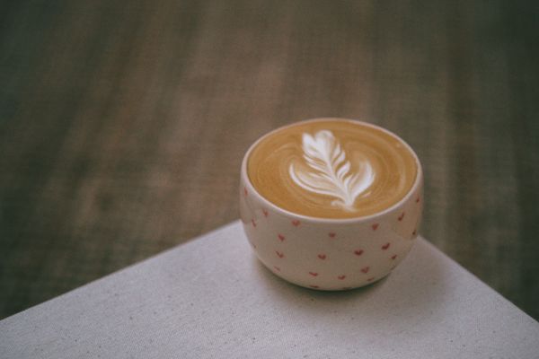 A latte with a rosetta poured into a small patterned cup