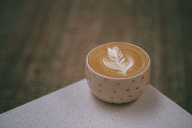 A latte with a rosetta poured into a small patterned cup