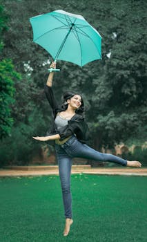一位年轻的南亚女子在公园里快乐地用雨伞跳舞
