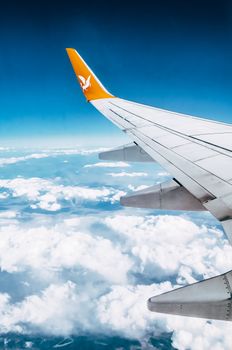 View from an airplane wing flying high above the clouds, symbolizing freedom and travel.