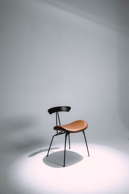 Free A single black and brown chair sitting under studio lighting, emphasizing minimalist design. Stock Photo