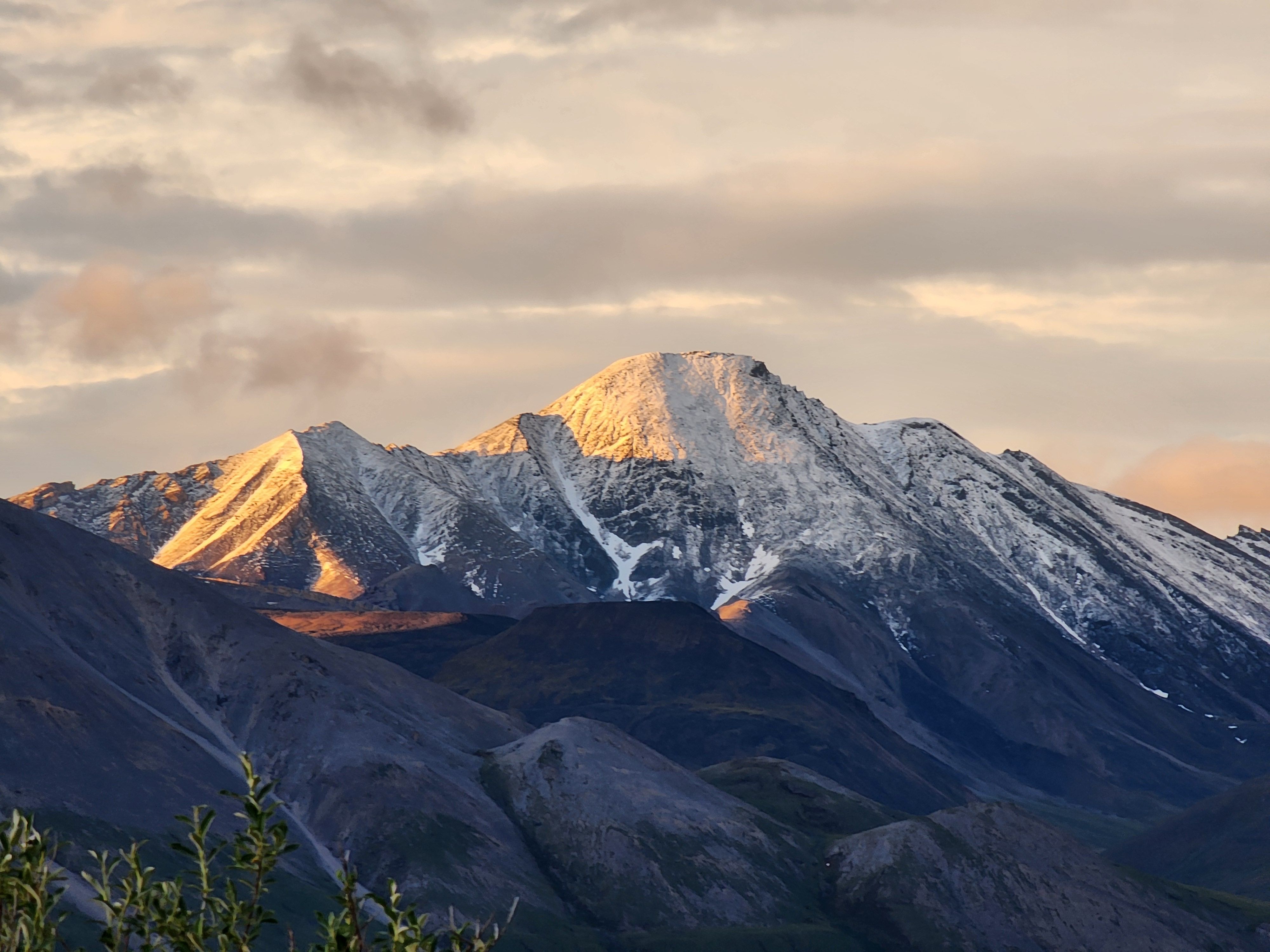 A mountain range with snow capped peaks at sunset · Free Stock Photo