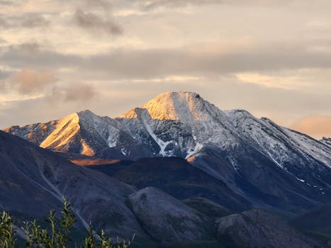 Snow-capped mountain peaks illuminated by the sunset, showcasing a breathtaking landscape view.