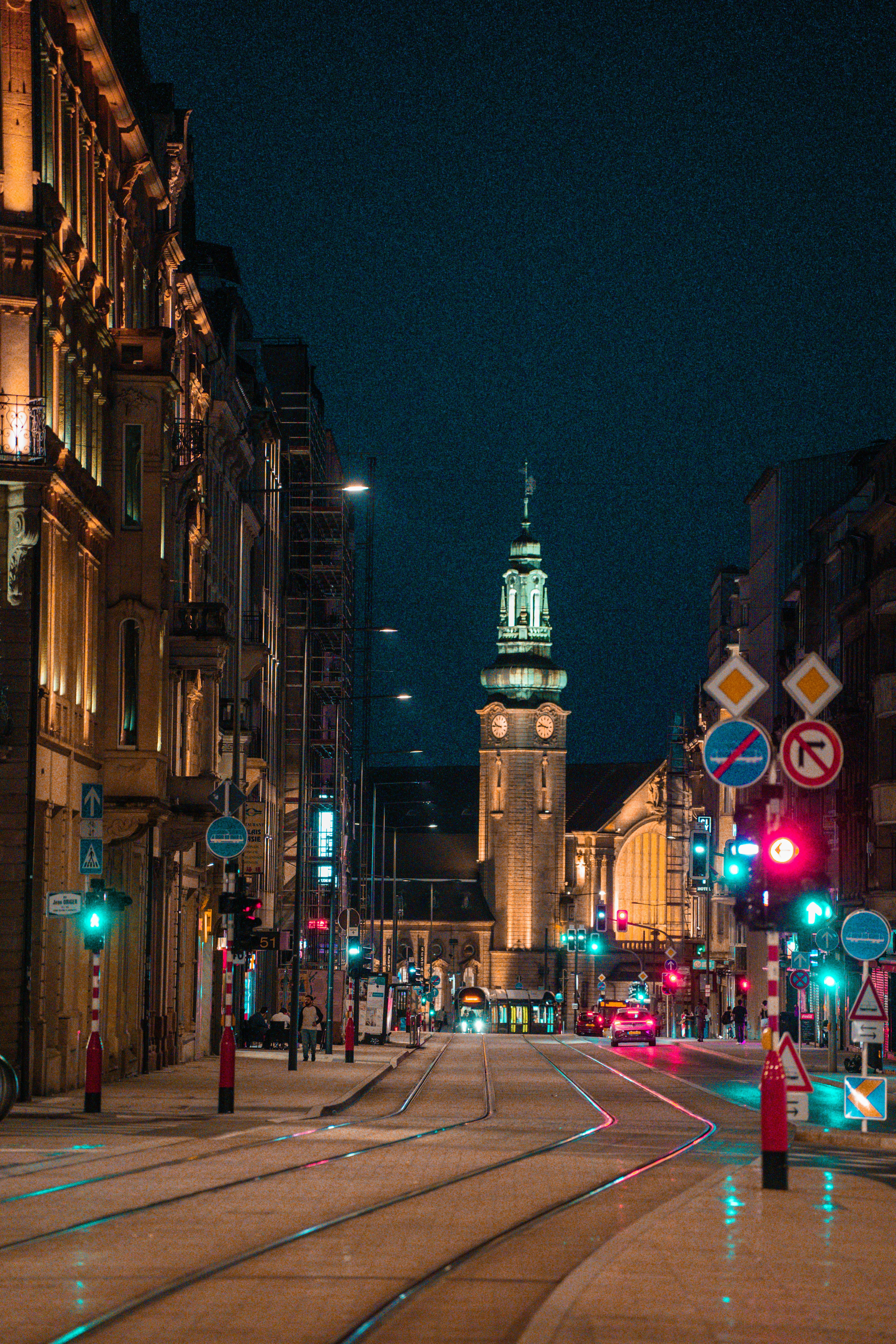 a city street at night with a clock tower