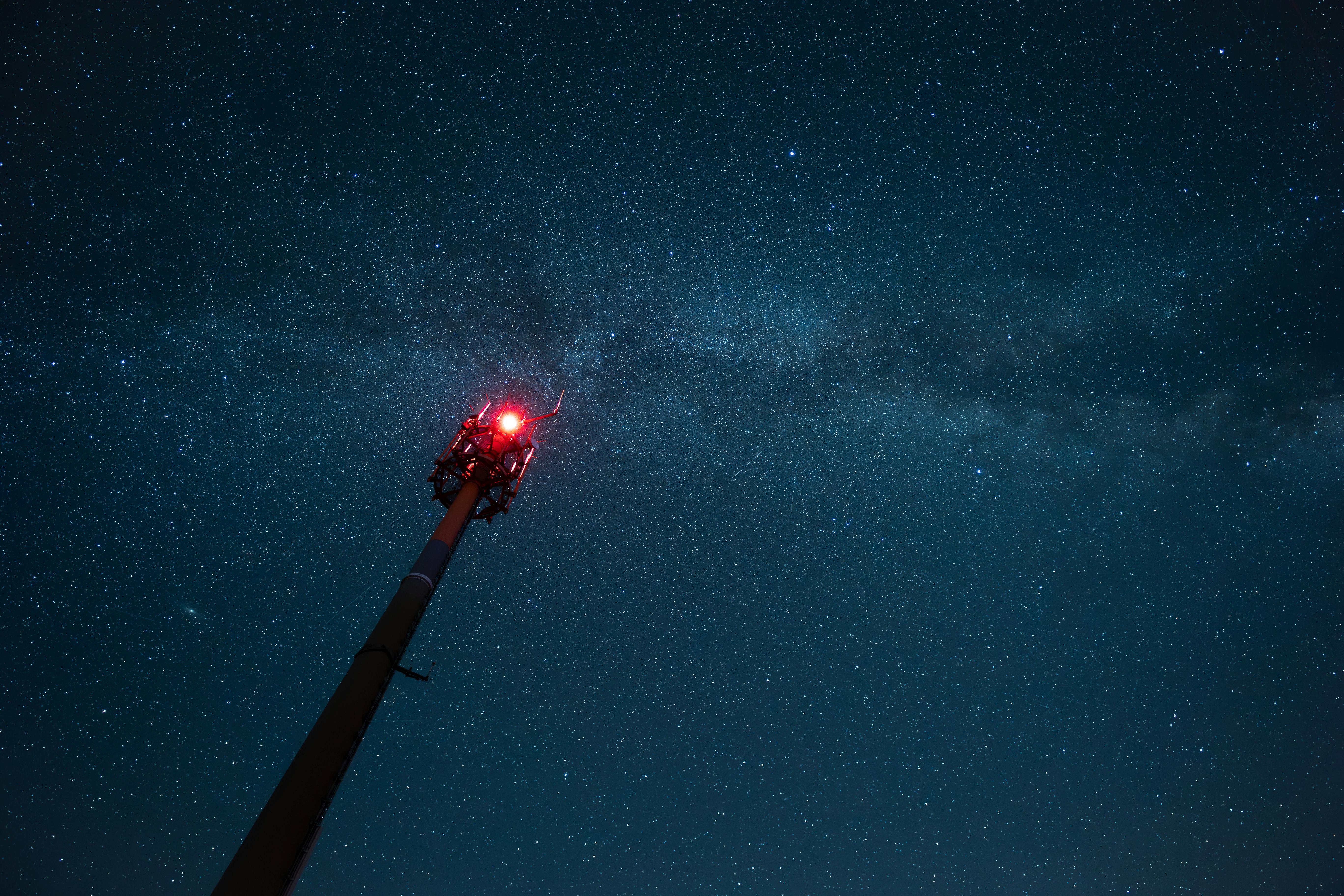 relay tower with red warning light against the night sky