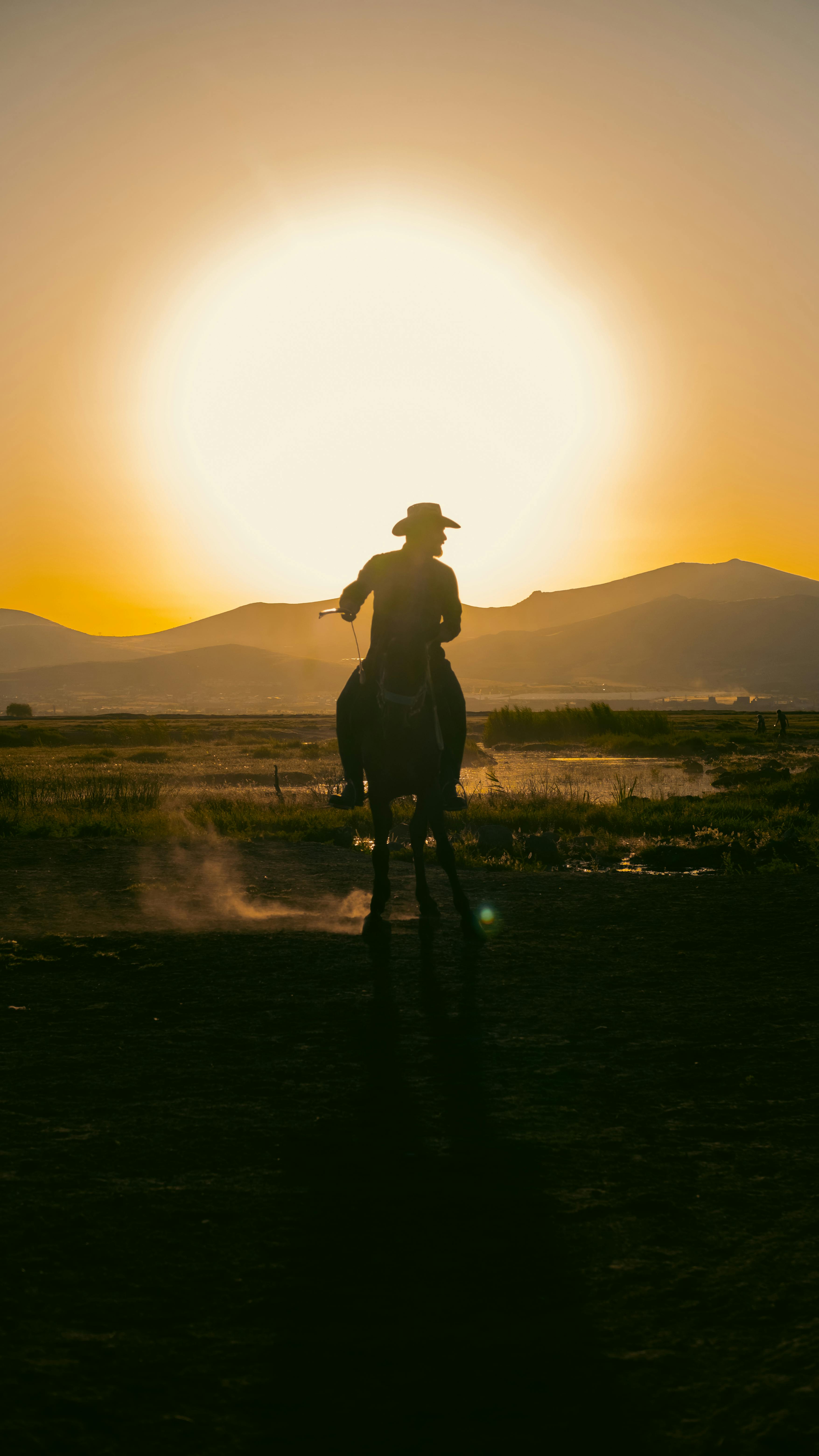 A cowboy rides a horse against a golden sunset in the scenic countryside of Kayseri, Türkiye.