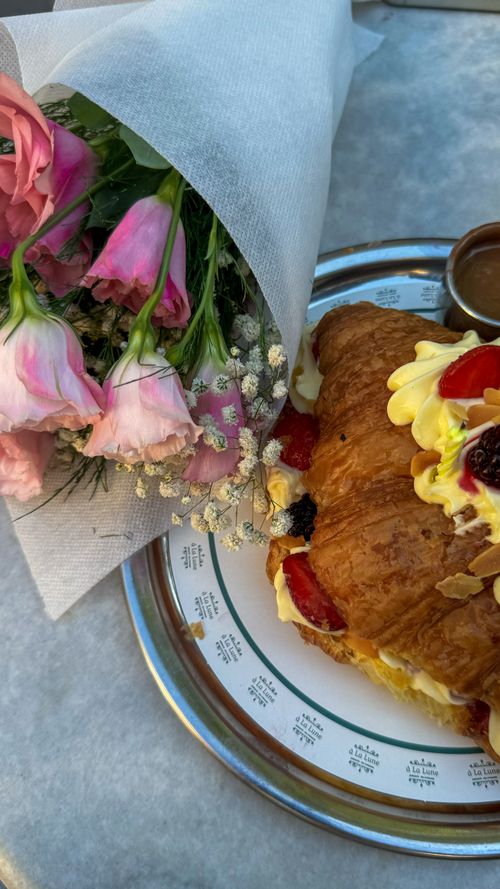 Free Delicious croissant with berries and cream, paired with a bouquet of fresh flowers on a table. Stock Photo