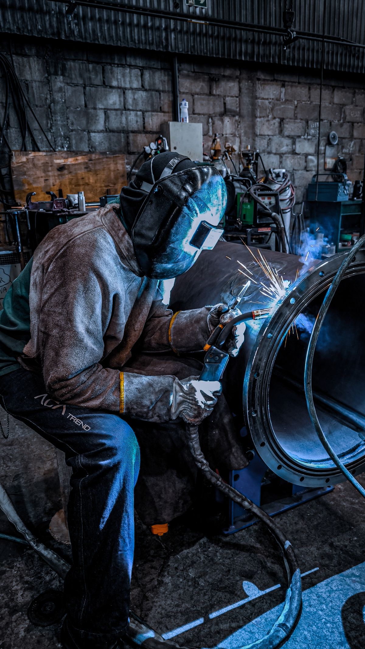Worker welding inside a factory, wearing full safety gear