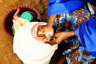 A woman is washing her hands with water from a bucket