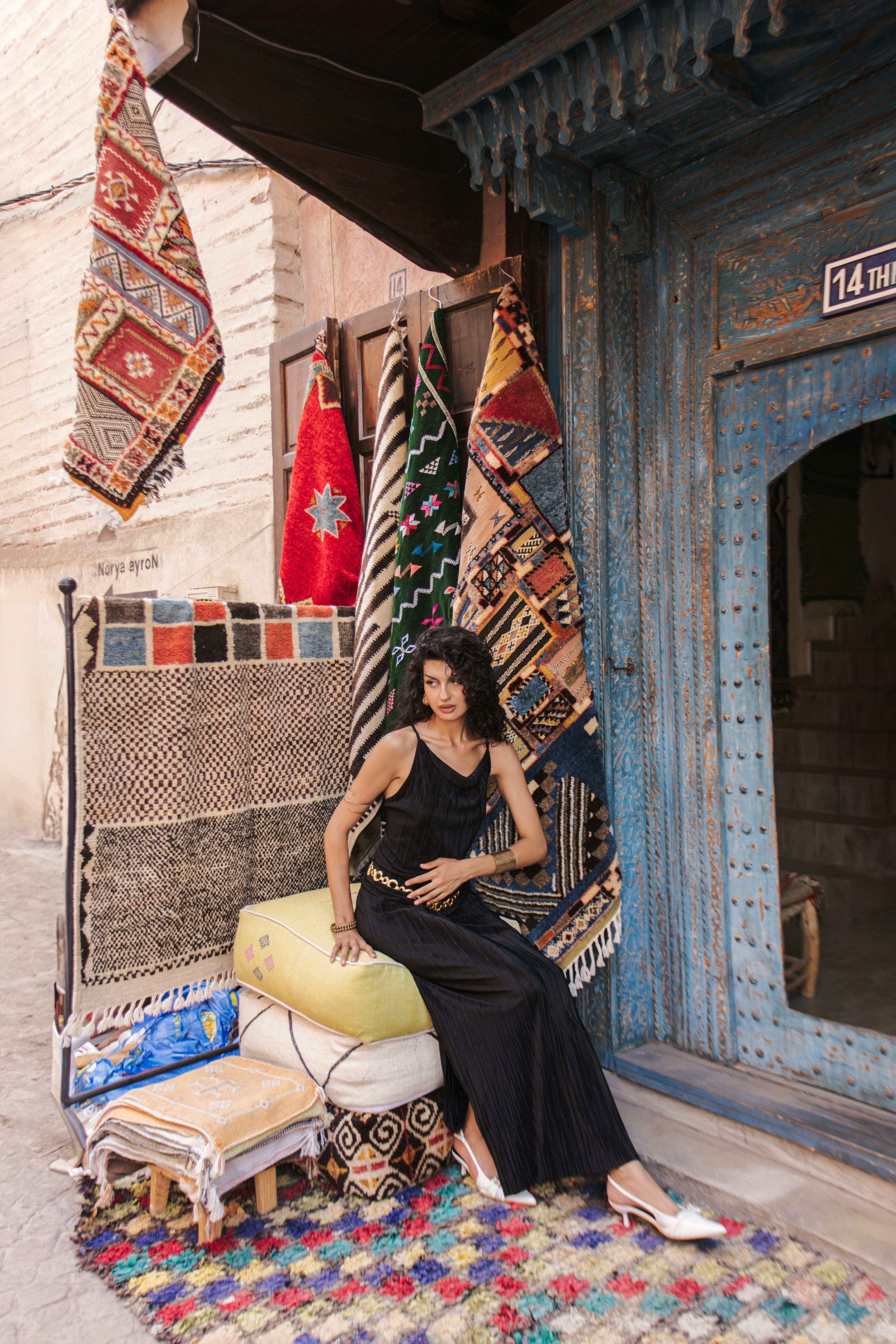 a woman in a black dress sitting on a rug