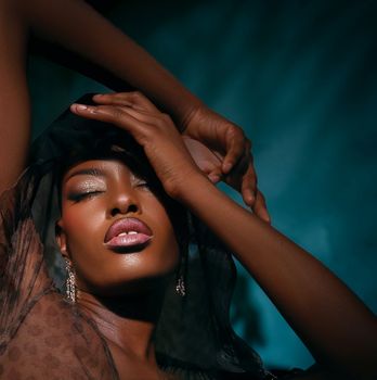 Elegant portrait featuring a woman with rich skin tone in dramatic lighting.