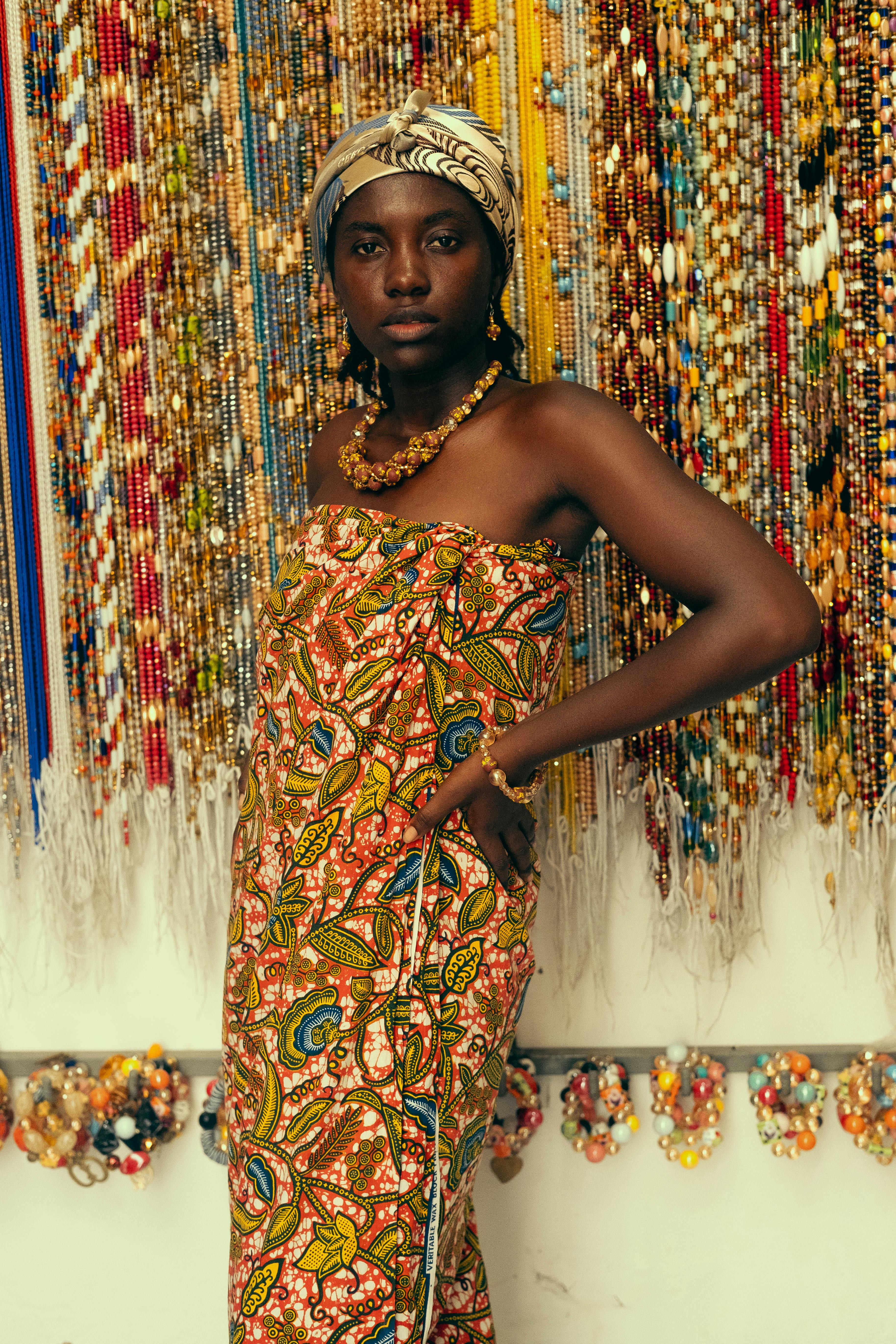 Portrait of a woman wearing vibrant African dress and jewelry, symbolizing cultural heritage.