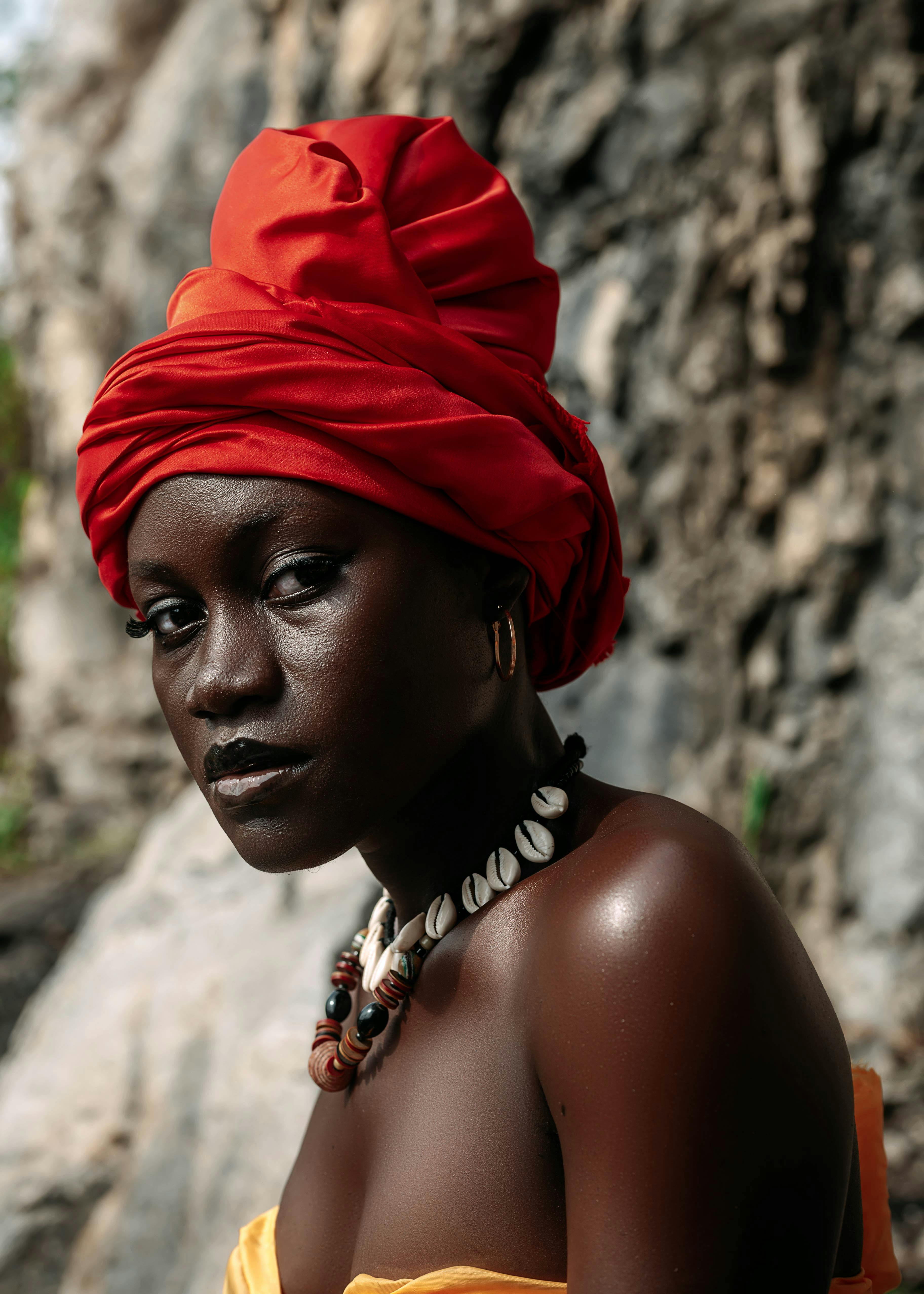 Stunning portrait of a woman in a red turban and jewelry, set in Kumasi, Ghana.