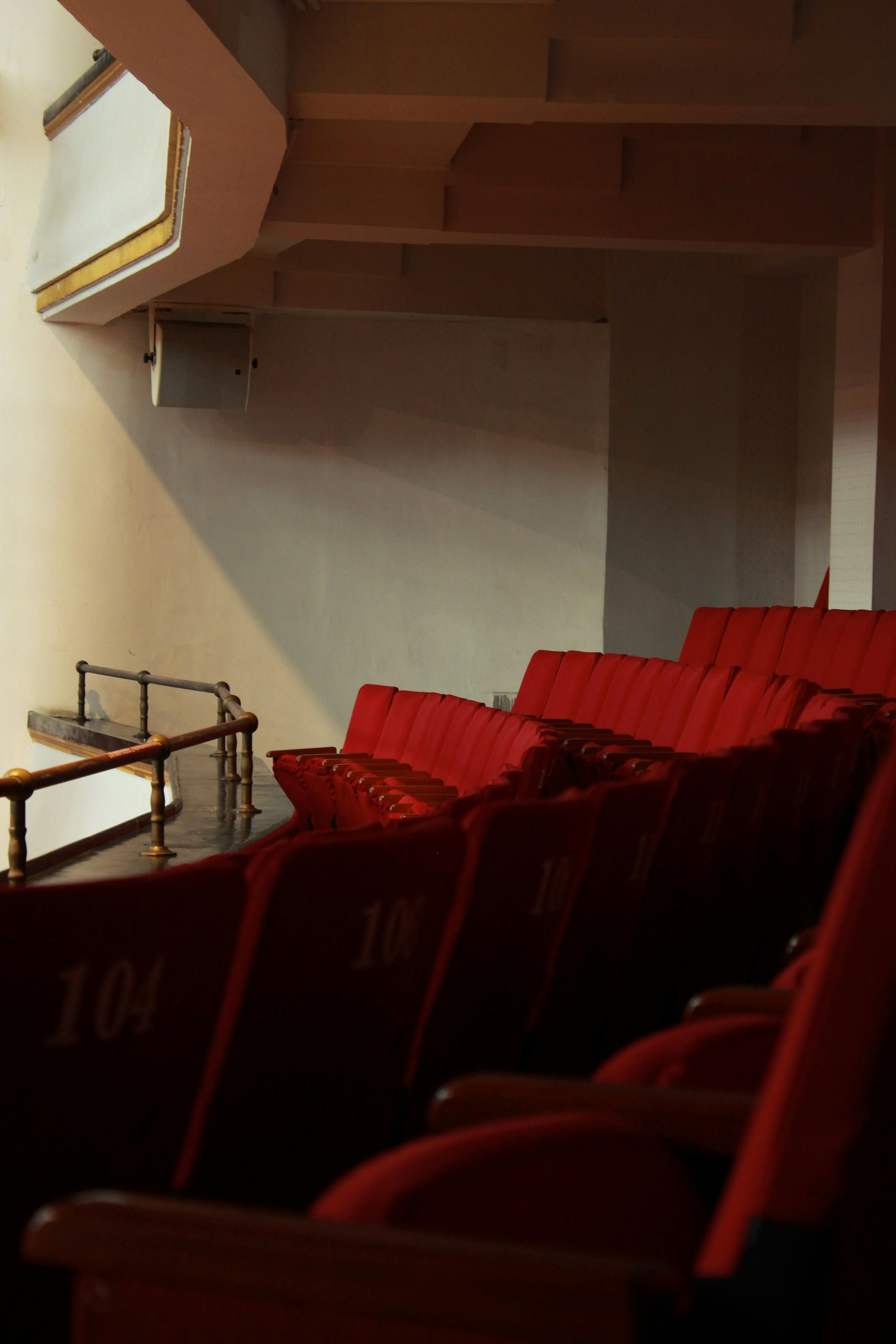 Free A row of empty red seats in a quiet, dimly lit auditorium with a serene atmosphere. Stock Photo