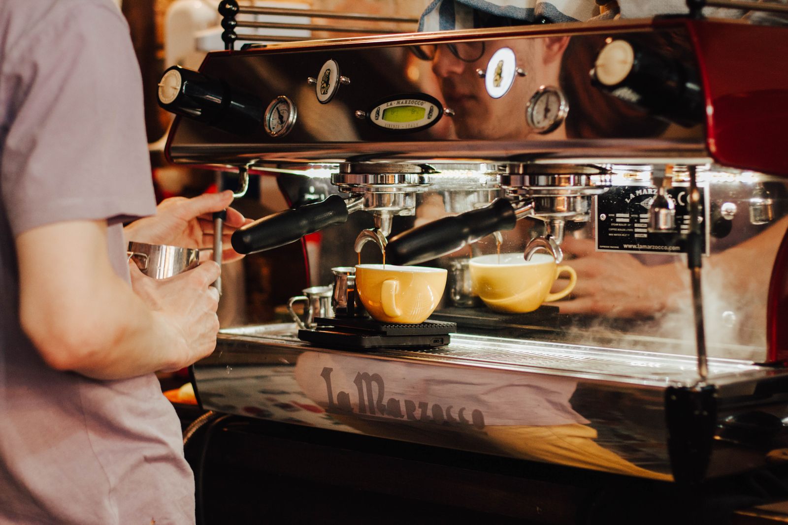 Hands operating the portafilter and steam wand of a home espresso machine