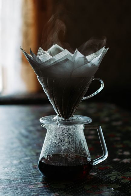 A hot and aromatic pour over coffee brewing on a table, showcasing steam and a serene atmosphere.