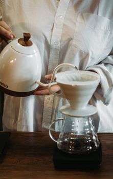 Close-up of a person using a pour over method to make coffee in a kitchen setting.