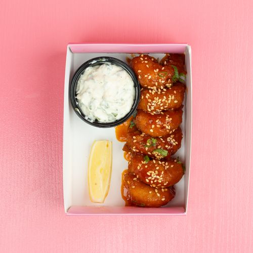 Free Top view of fried chicken bites with sesame seeds, sauce, and lemon in a pink box. Stock Photo
