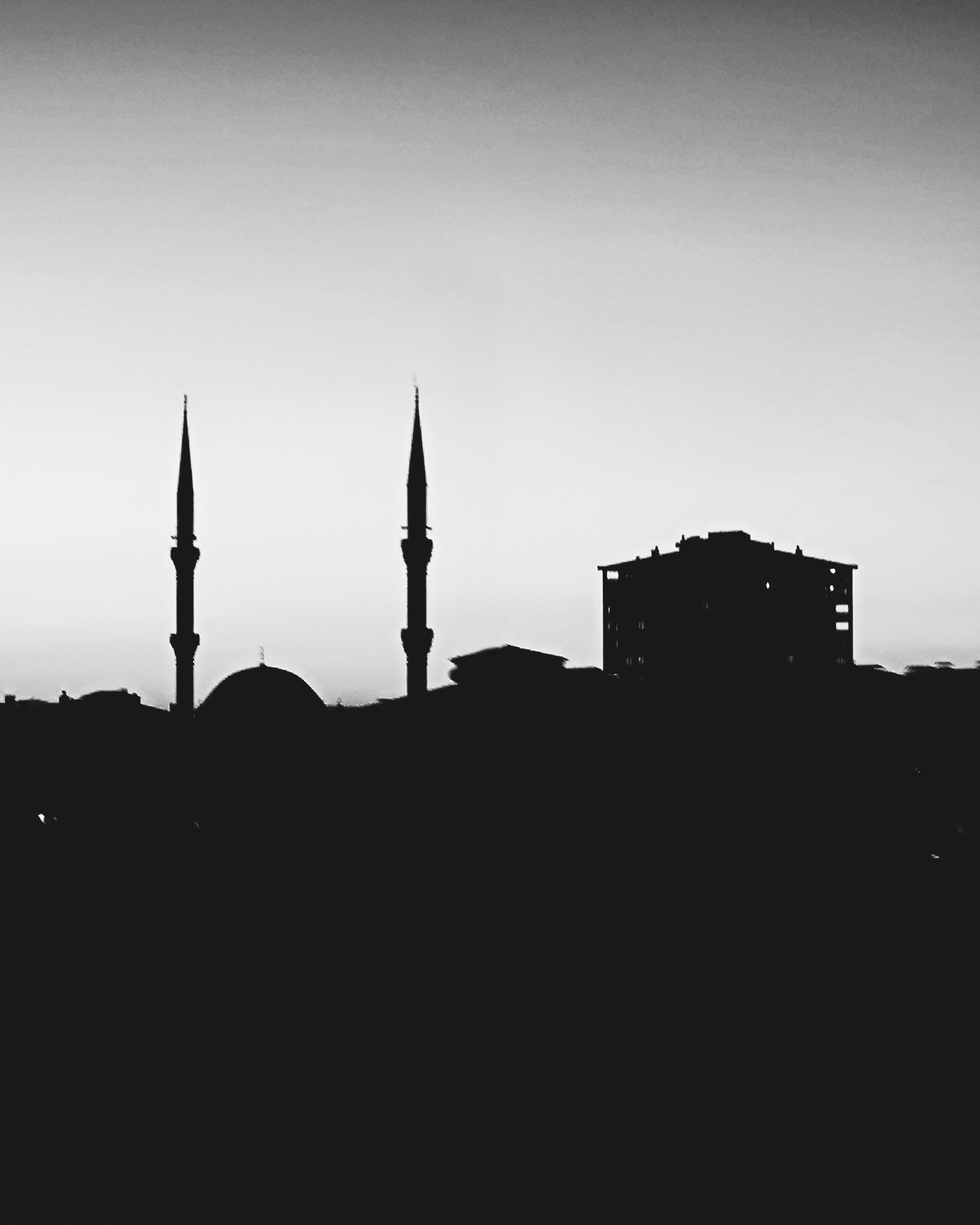 Dramatic black and white silhouette of minarets in Ankara at dusk, showcasing iconic cityscape.