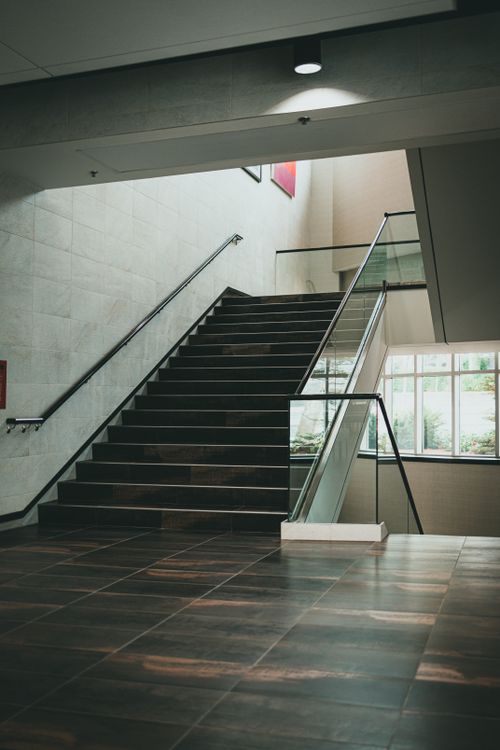 Free Spacious indoor staircase featuring sleek glass and metal design, ideal for contemporary architecture themes. Stock Photo