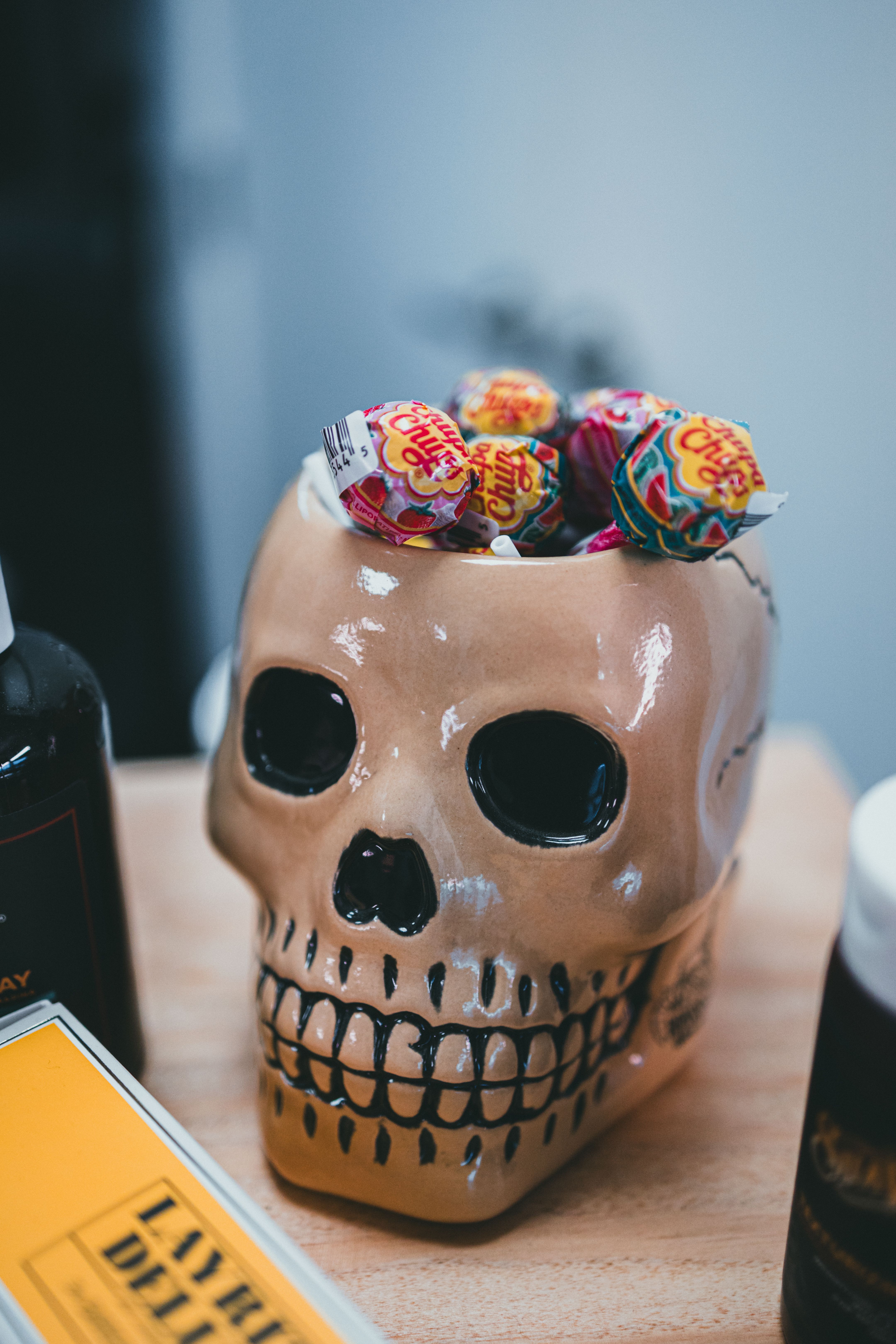 A ceramic skull filled with colorful lollipops, ideal for Halloween decoration.