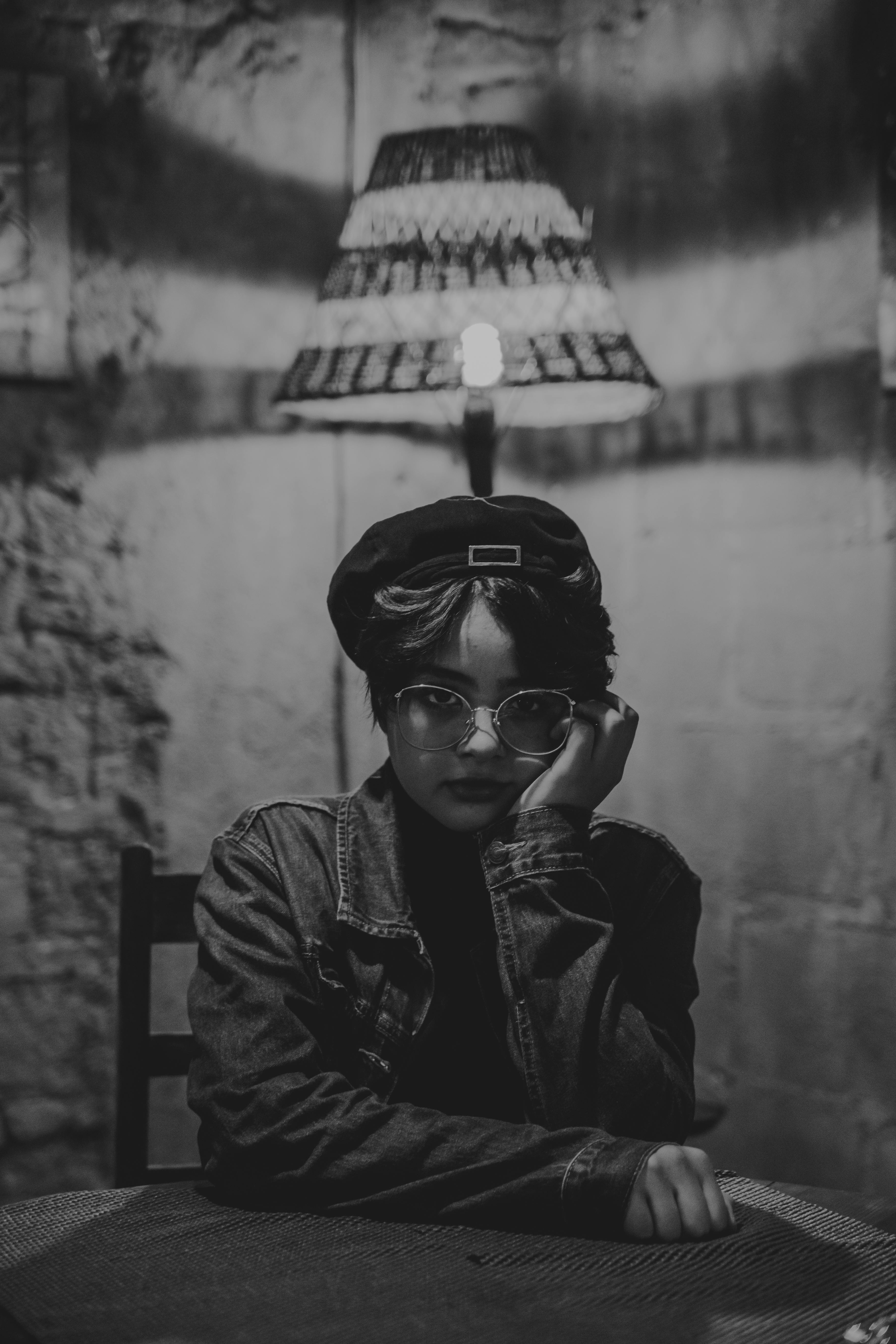 Black and white portrait of an adult wearing eyewear, showcasing a retro style in a dimly lit indoor setting.