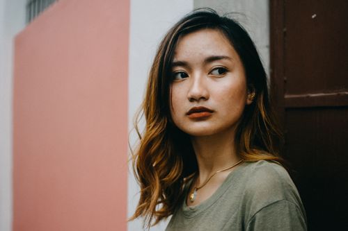 Free Close-up portrait of a young woman with contemplative expression against a textured wall. Stock Photo