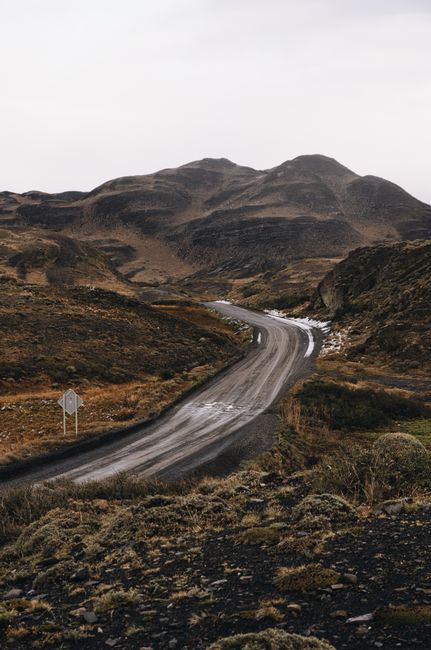 A moody dirt road winding through the Magallanes mountains in Chile.