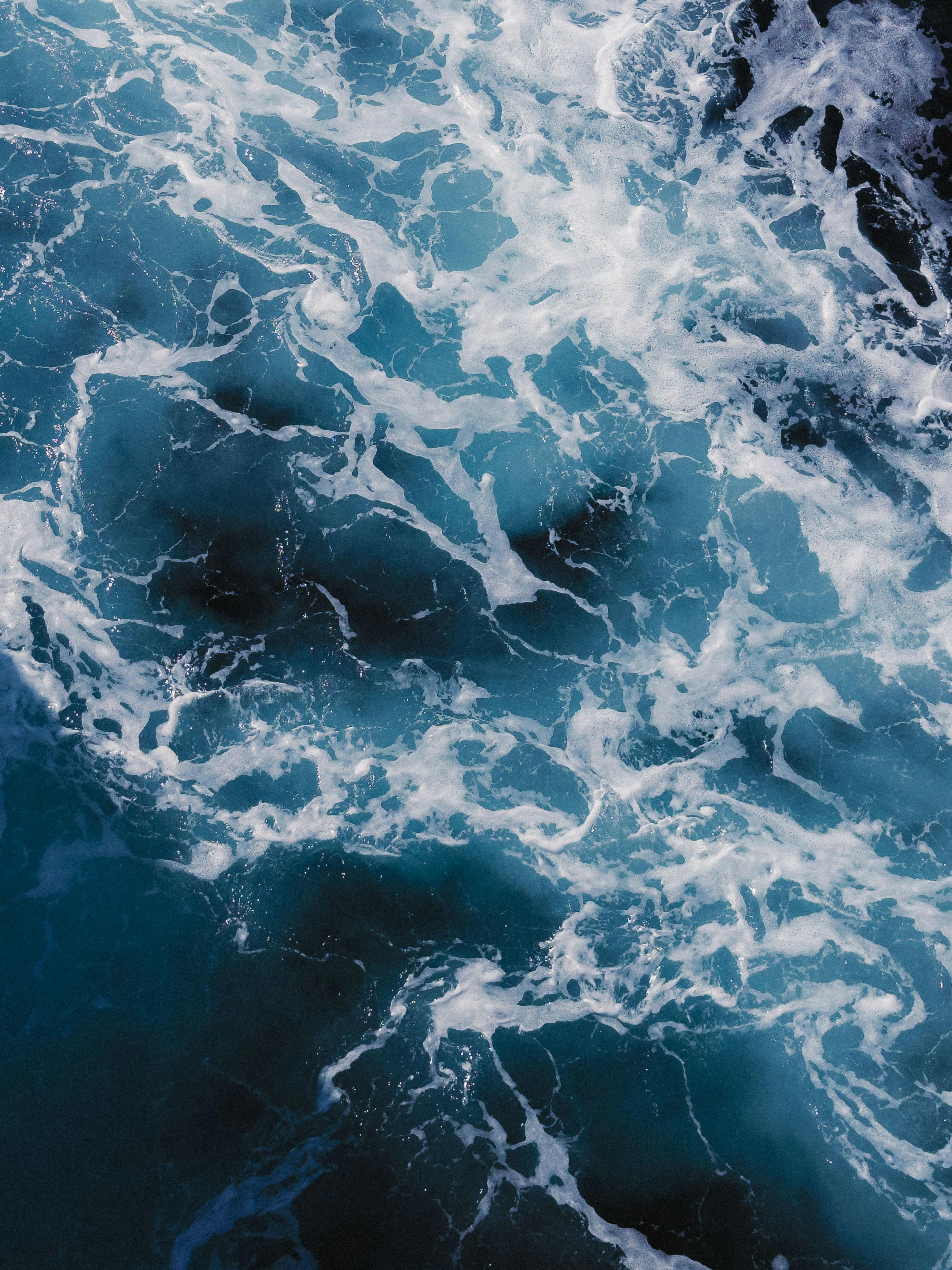 Dynamic ocean waves create mesmerizing patterns of foam and turquoise hues, evoking a sense of adventure and freedom.