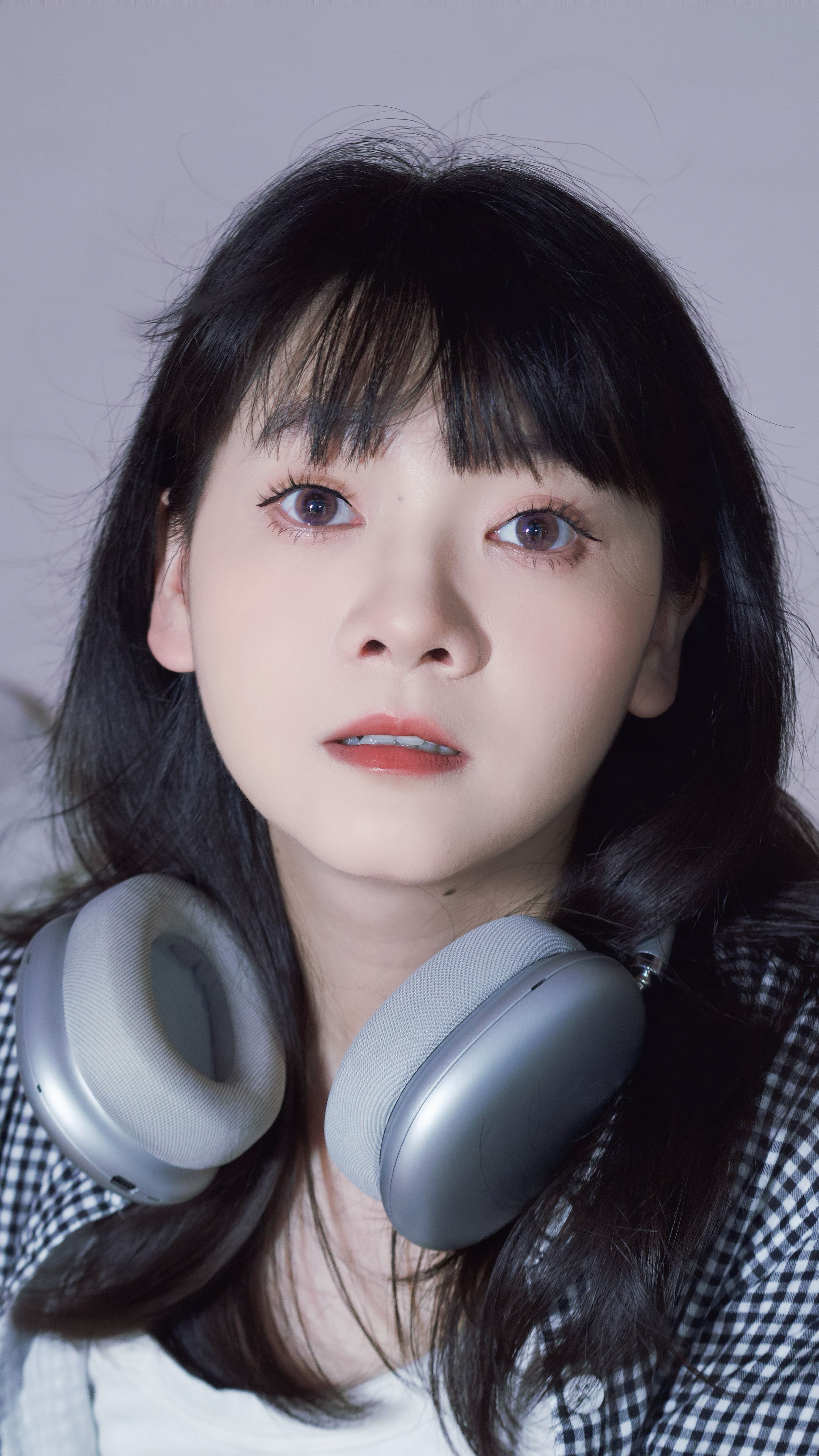 Portrait of a young woman with headphones, expressing curiosity.