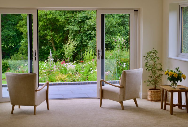 A cozy counselling room interior with armchairs and greenery viewed through glass doors