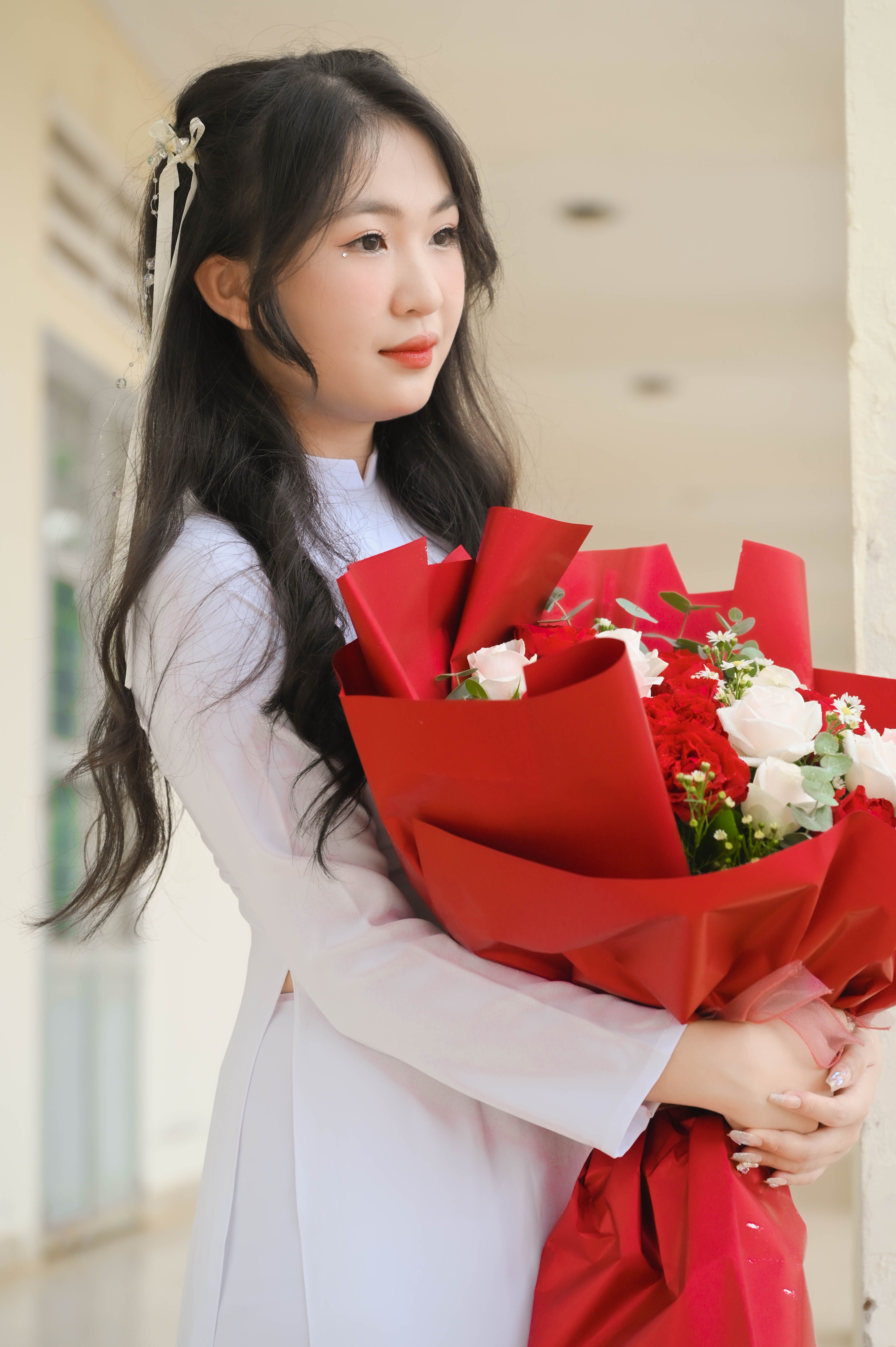 A woman in a white dress holding a bouquet of red roses · Free Stock Photo