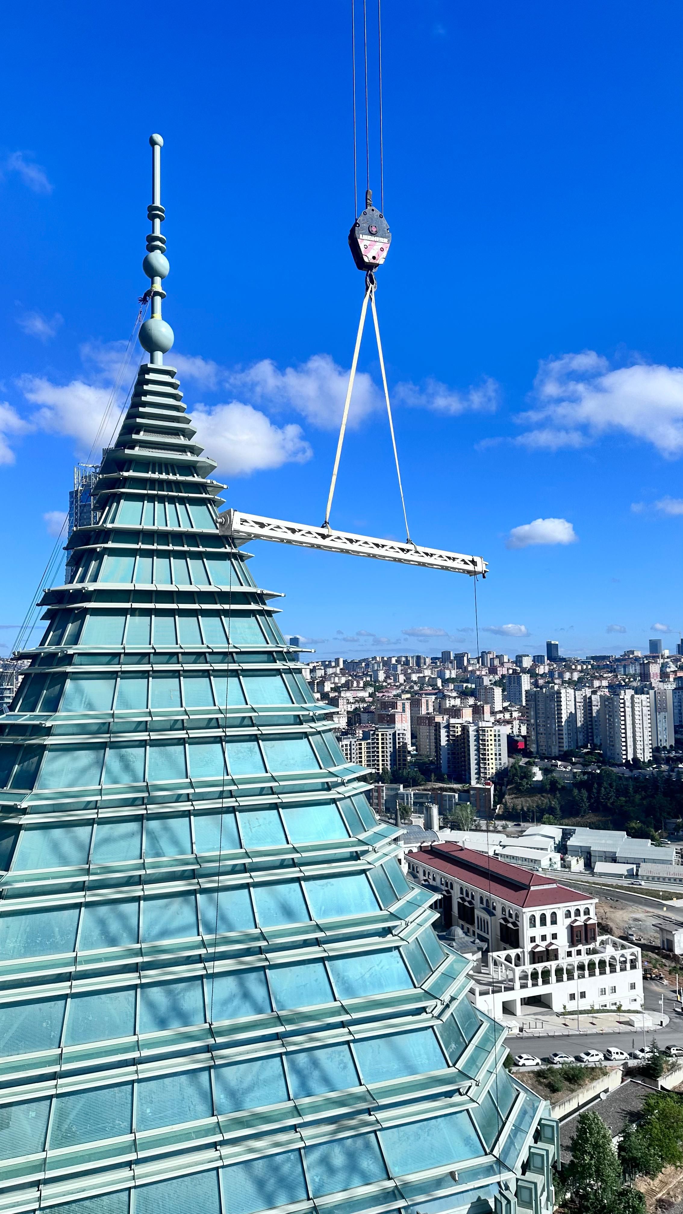 Urban skyline with modern skyscraper and construction crane under clear blue sky.