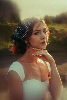 A vintage style portrait of a woman with a headscarf and thoughtful expression during sunset.