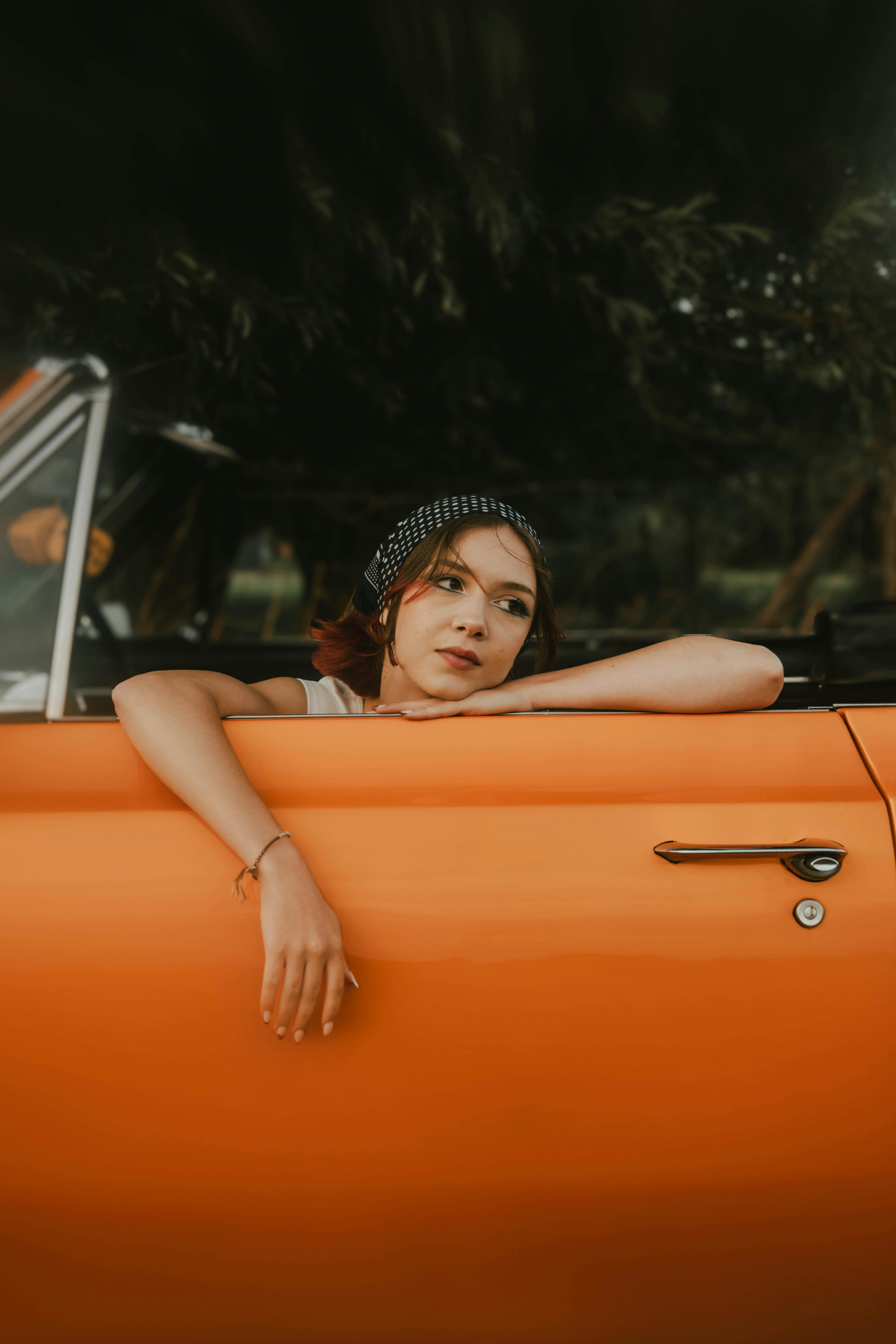 young woman leaning on door of a vintage convertible car