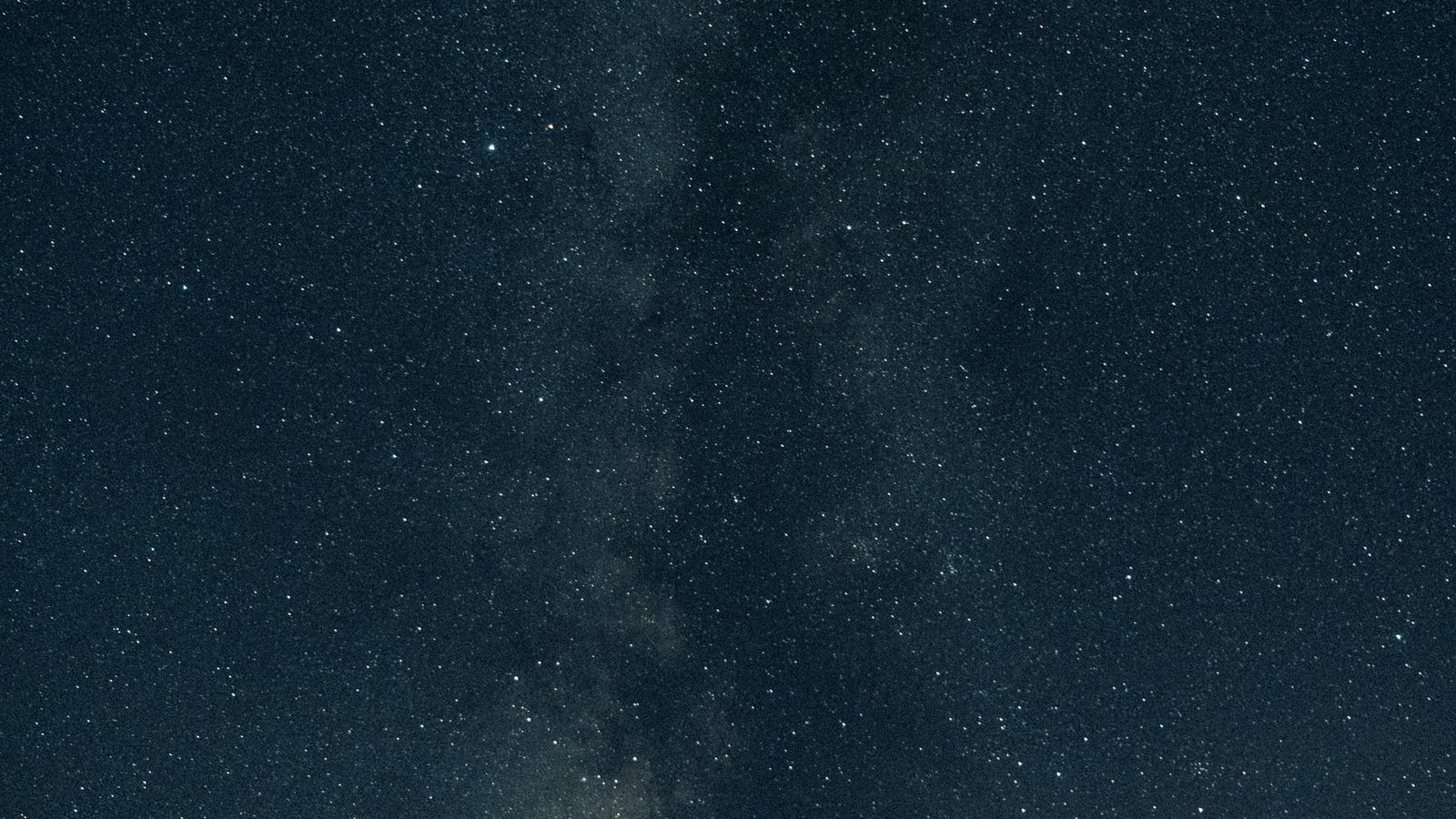 Die Milchstraße über Hügeln in der Wüste bei Nacht