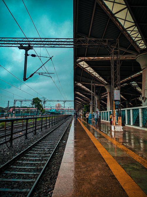 Free A bustling urban railway station with modern architecture on a rainy day, capturing commuter activity and reflections. Stock Photo