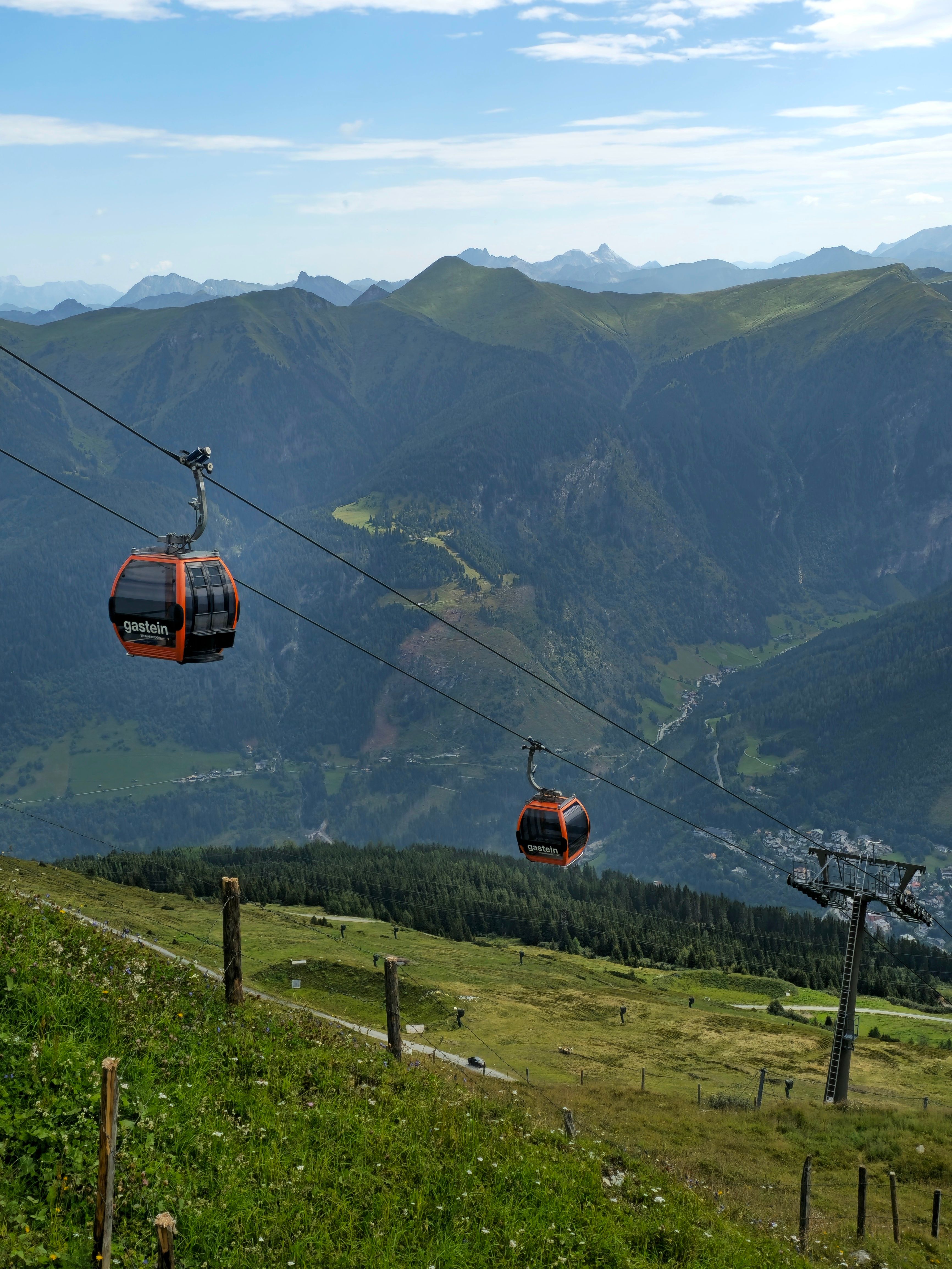 Cable cars gliding over picturesque Badgastein in the Austrian Alps, offering stunning views of the mountains.