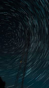 Captivating view of swirling star trails around a communication tower under a clear night sky.