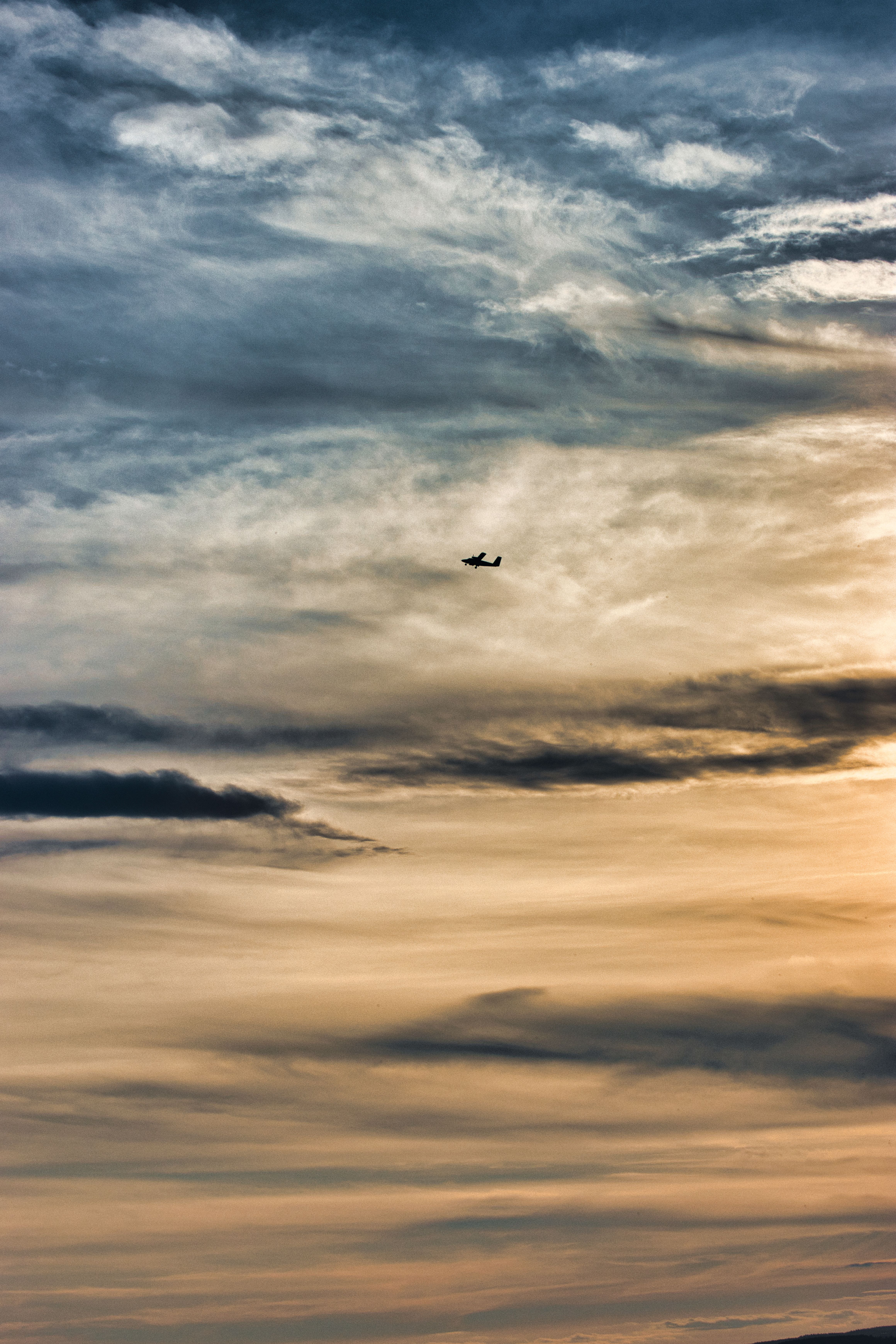 A plane flying through the sky at sunset · Free Stock Photo