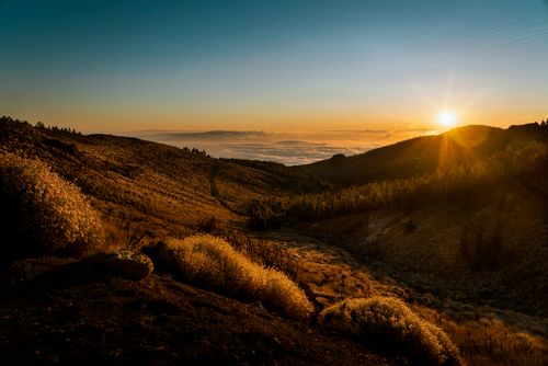 Free A breathtaking view of the sun setting over rolling mountains and lush valleys. Stock Photo
