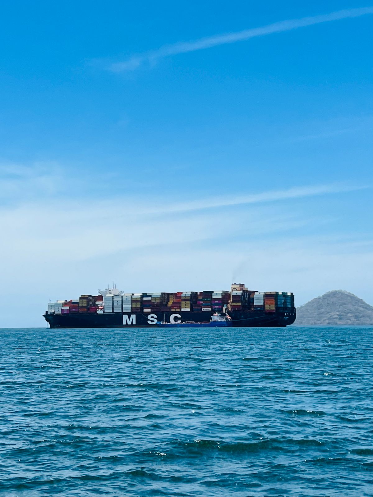 Large cargo ship carrying containers under a clear blue sky