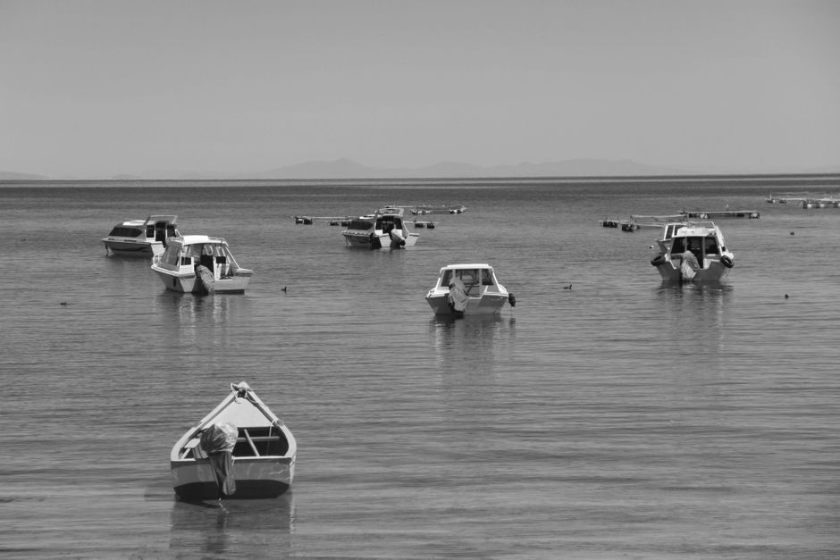 Peaceful black and white shot of moored boats on calm waters in El Alto, Bolivia.
