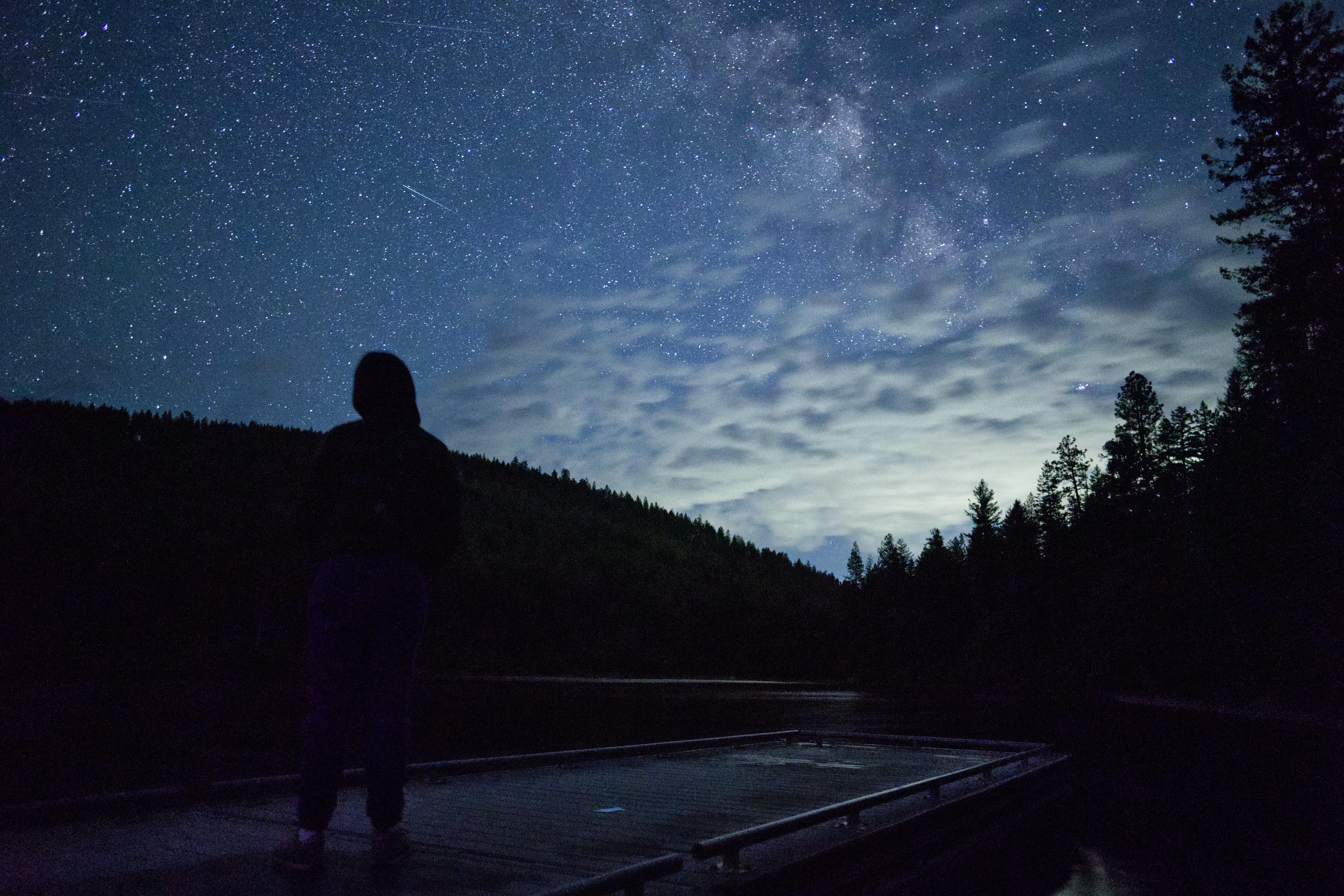 a person standing on a boat looking up at the stars