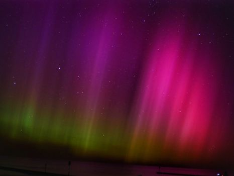 Vibrant aurora borealis with colors in the night sky over the Baltic Sea, viewed from Kołobrzeg, Poland.